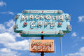 Vintage teal and orange Magnolia Cafe sign against a bright blue sky on South Congress Avenue in Austin, Texas